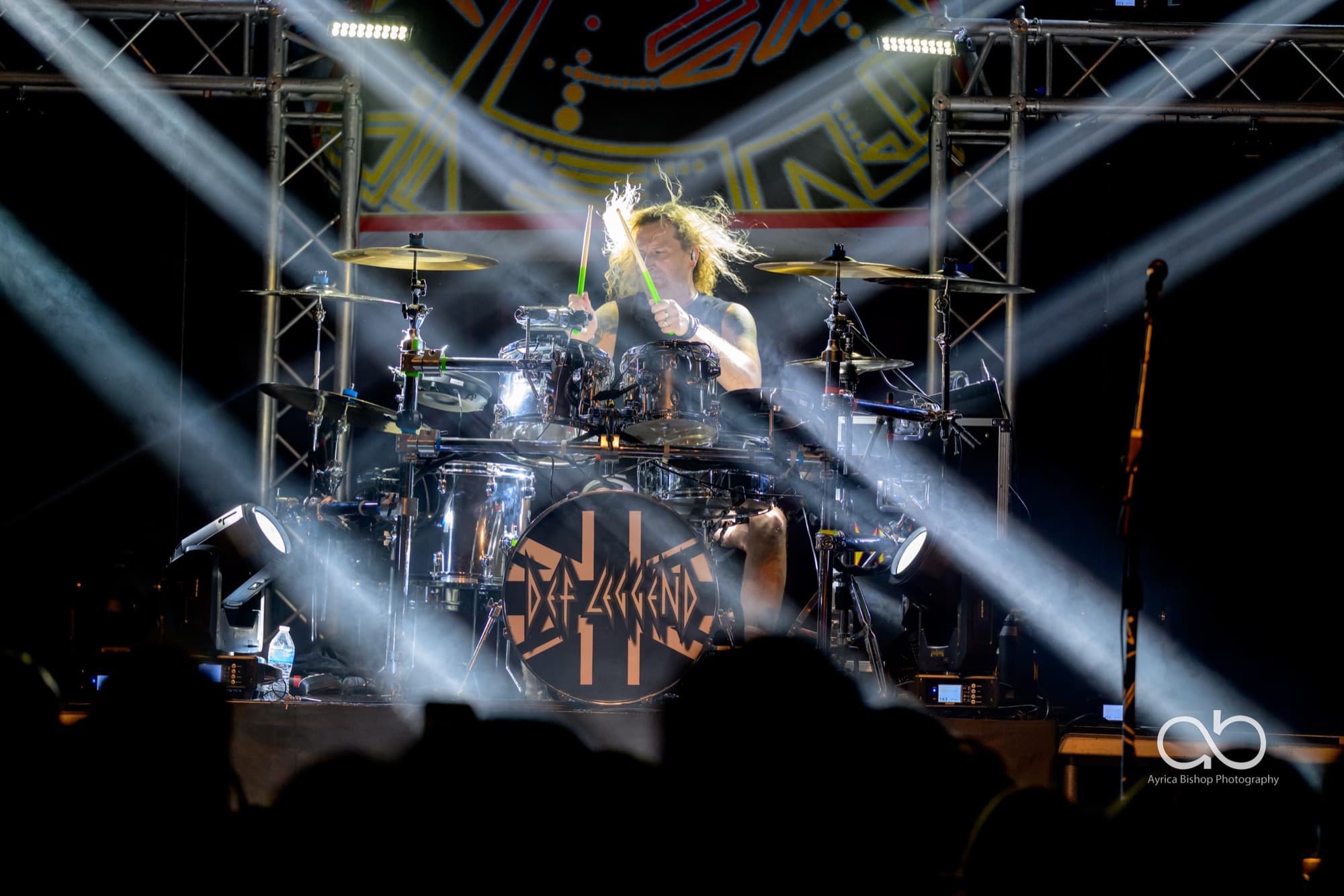 Def Leggend drummer performing under crossing light beams